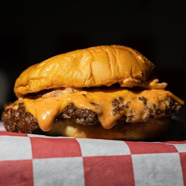 Bricked Burgers' cheeseburger with melted orange cheese and caramelized onions on a red and white checkered paper.